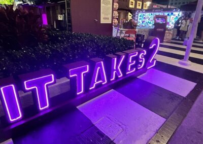 It Takes 2 illuminated purple sign